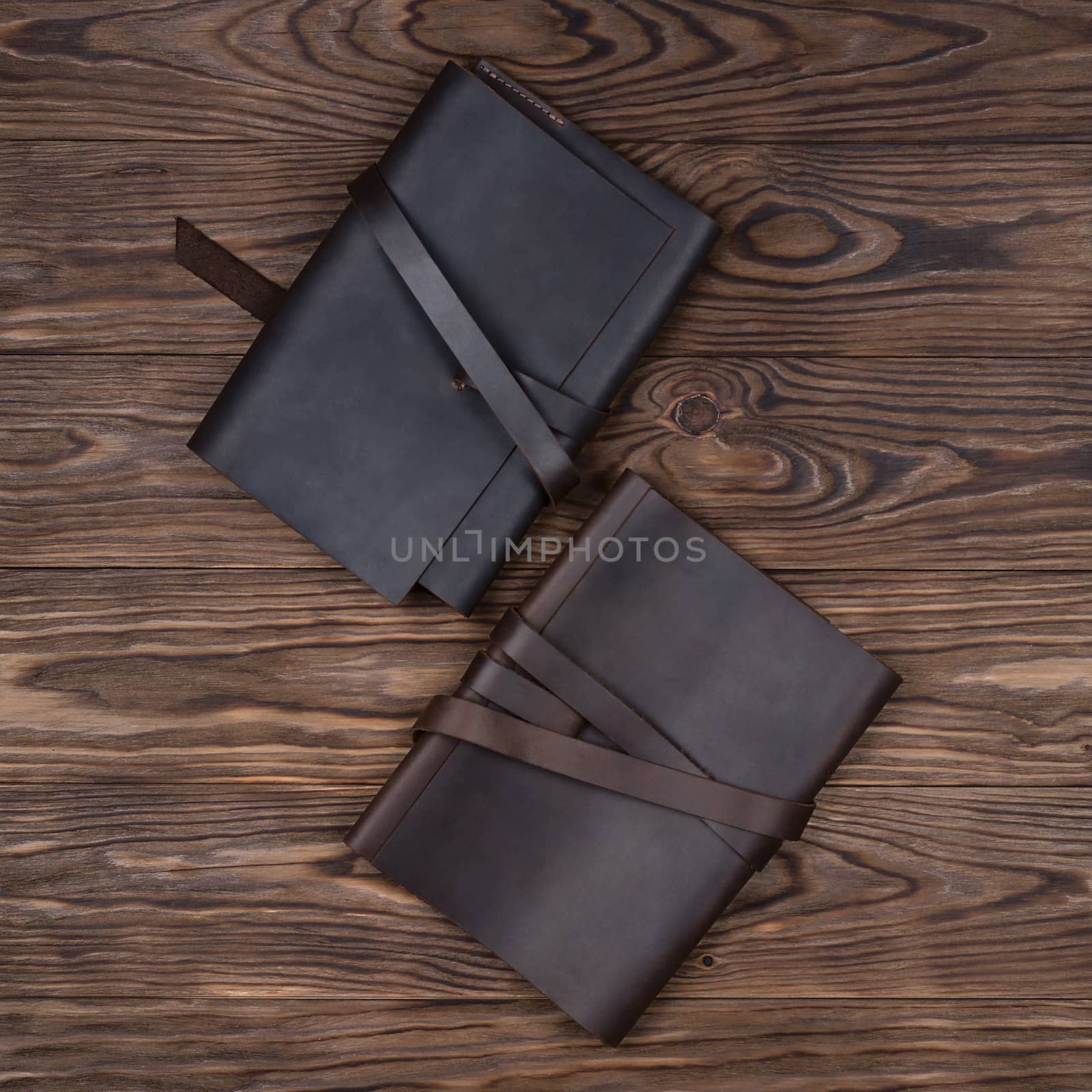 Black and brown handmade leather notebook cover with notebooks on wooden background. Stock photo of luxury business accessories. Up to down view.