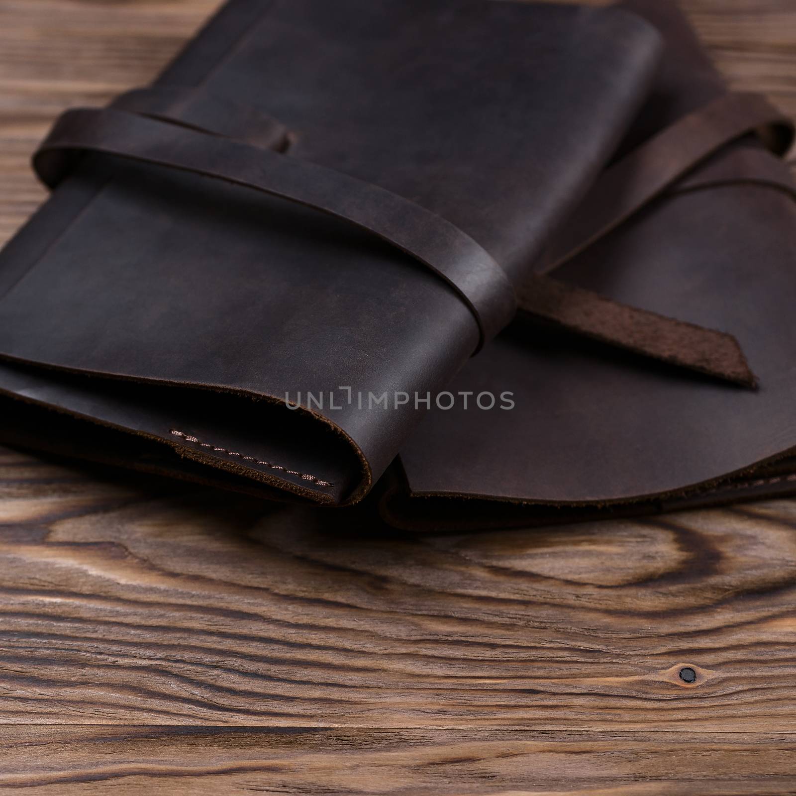 Two brown handmade leather notebook covers on wooden background. Stock photo of luxury business accessories. by alexsdriver