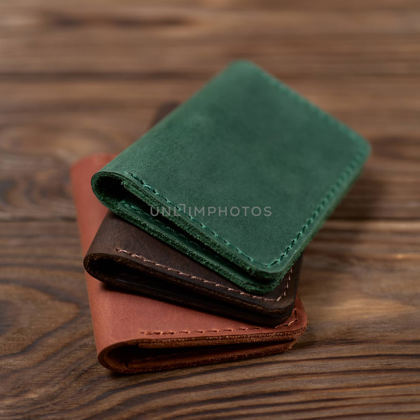 Three two-pocket leather handmade cardholder. Cardholders lies one on another. Stock photo on blurred background.