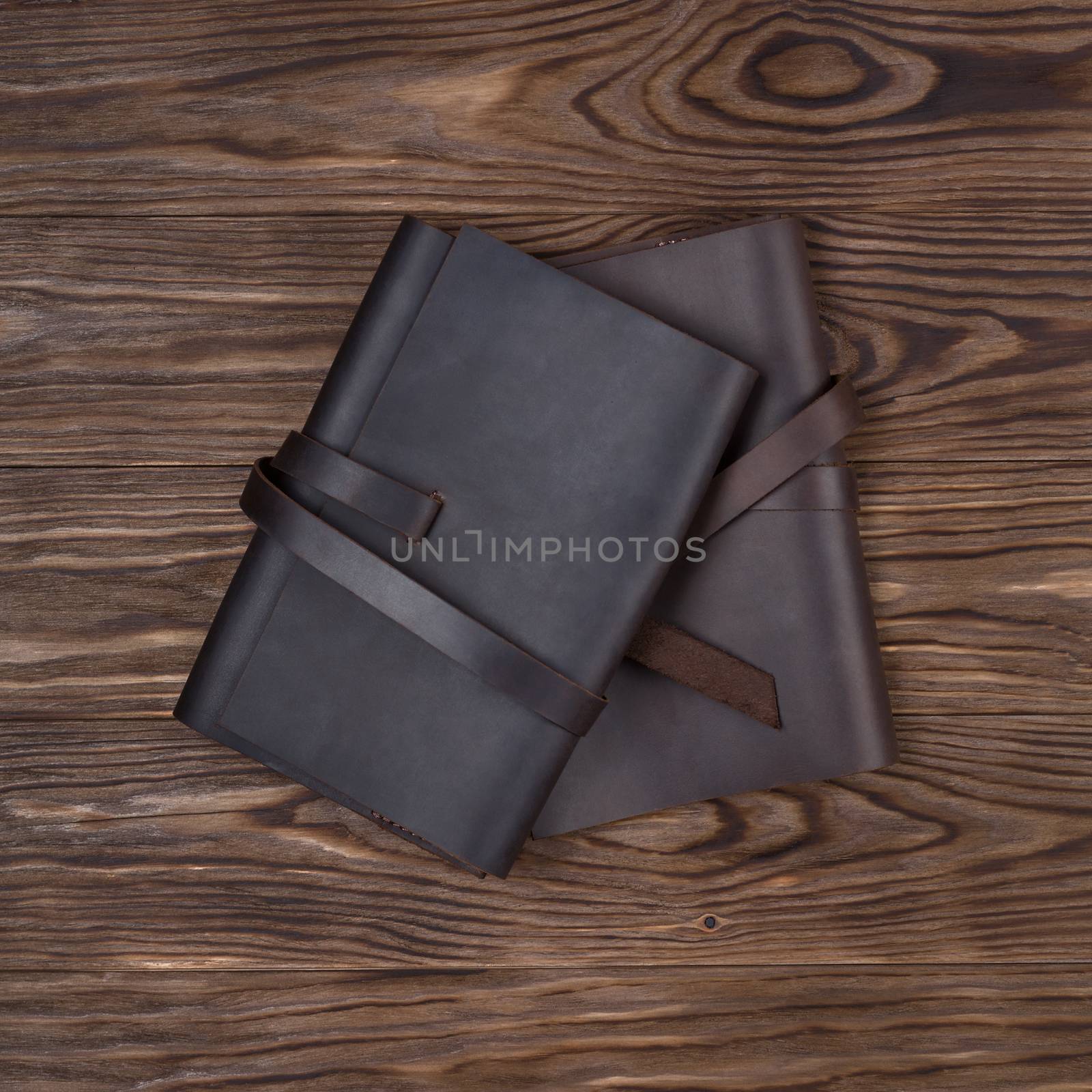 Black and brown handmade leather notebook covers on wooden background. Stock photo of luxury business accessories. Up to down view. by alexsdriver