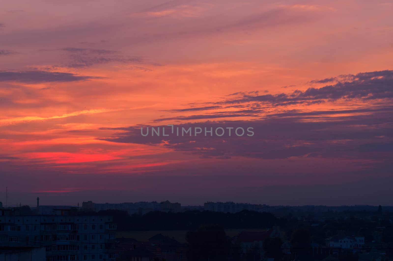 Orange evening sky with blurred sun on horizon trough fence. Creative idea- underexposed photo. by alexsdriver