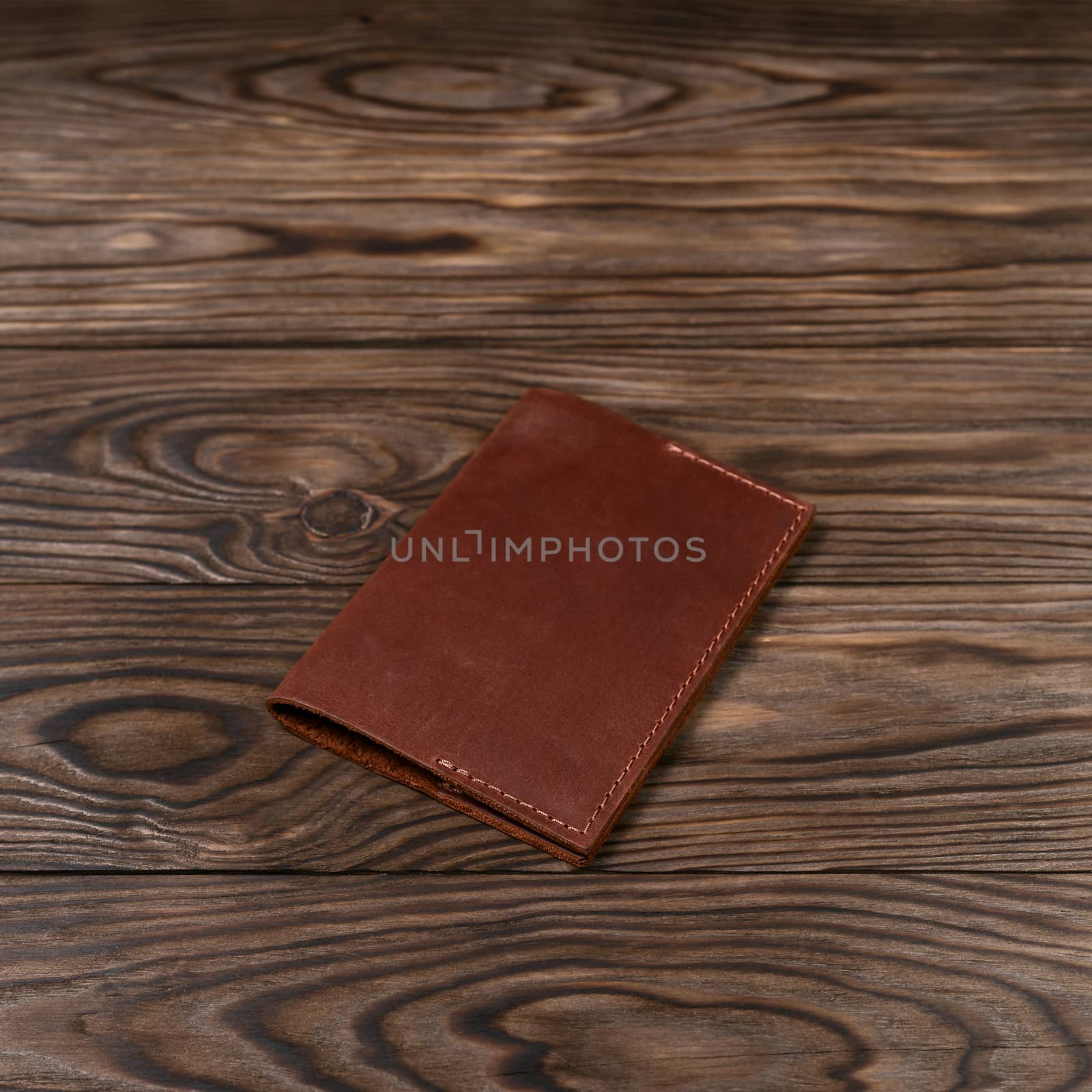 Ginger color handmade leather passport cover on wooden textured background. Businessman`s accessory.