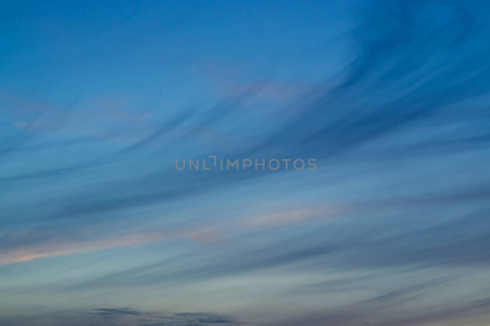Blue evening sky with blurred sun on horizon trough fence. Creative idea- underexposed photo. by alexsdriver