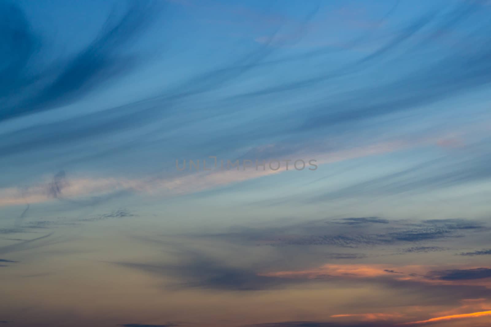 Blue evening sky with blurred sun on horizon trough fence. Creative idea- underexposed photo. by alexsdriver