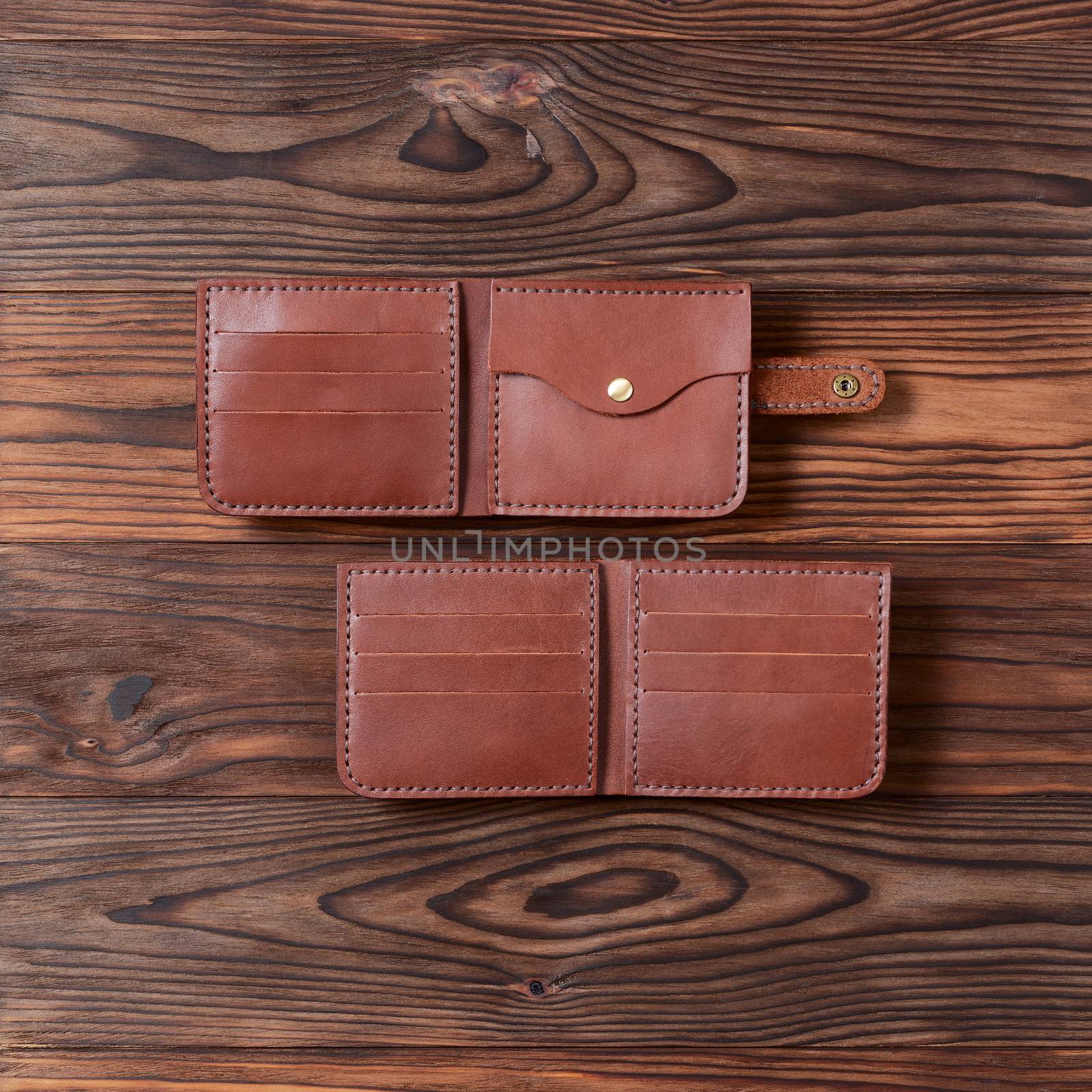 Two red color handmade leather wallets on wooden textured background. Up to down view. Wallet stock photo.