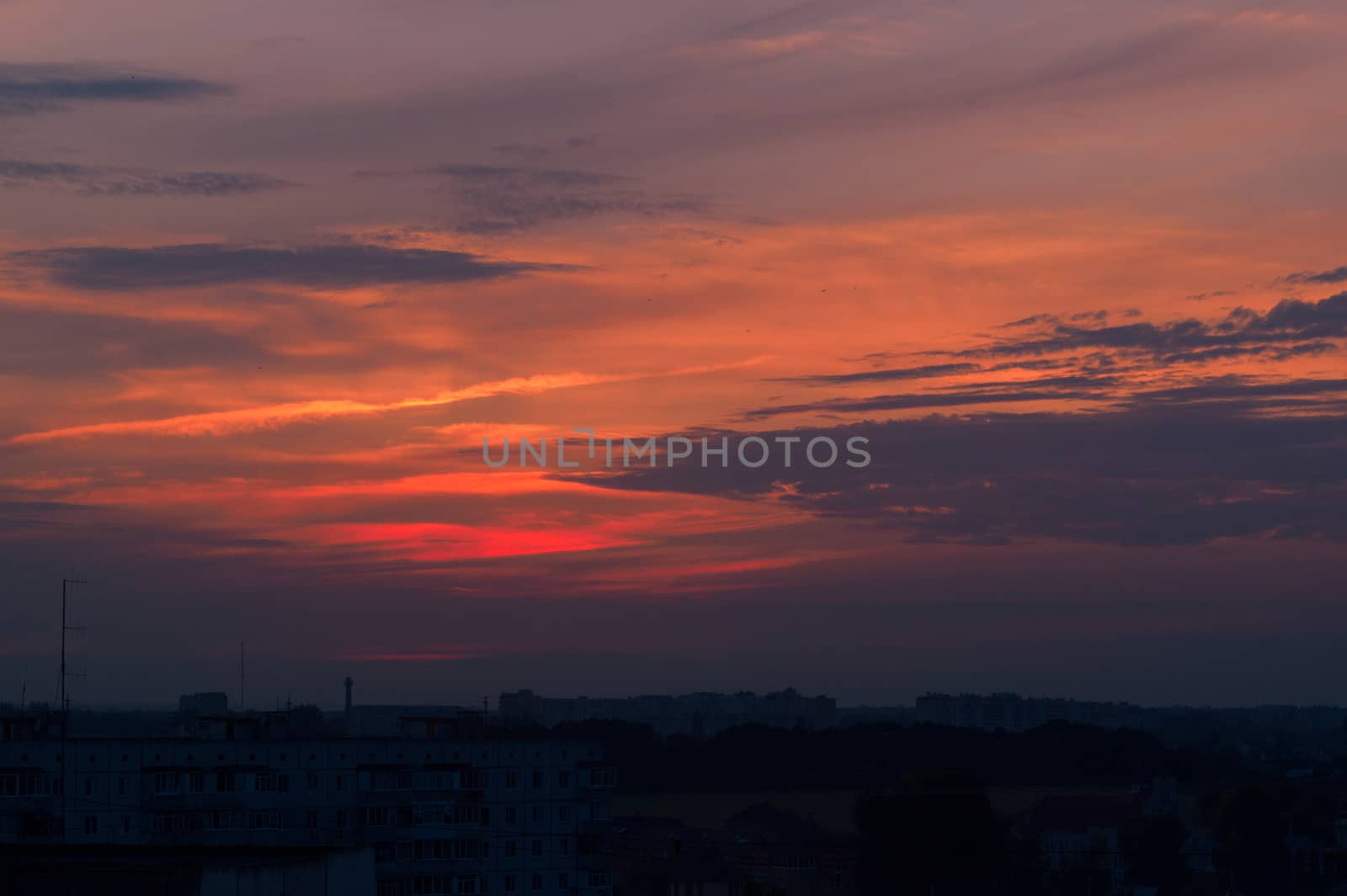 Orange evening sky with blurred sun on horizon trough fence. Creative idea- underexposed photo.