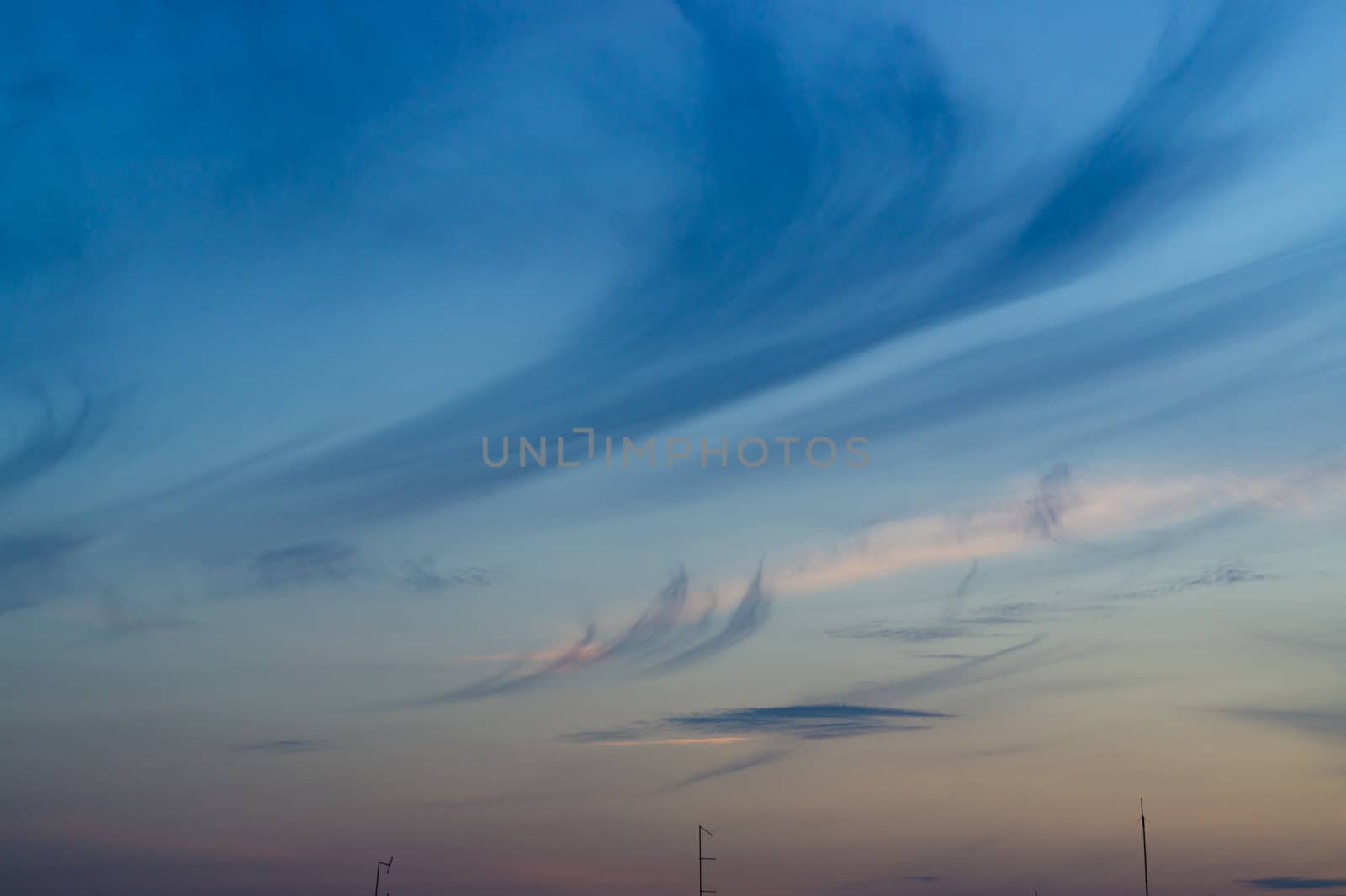 Blue evening sky with blurred sun on horizon trough fence. Creative idea- underexposed photo. by alexsdriver