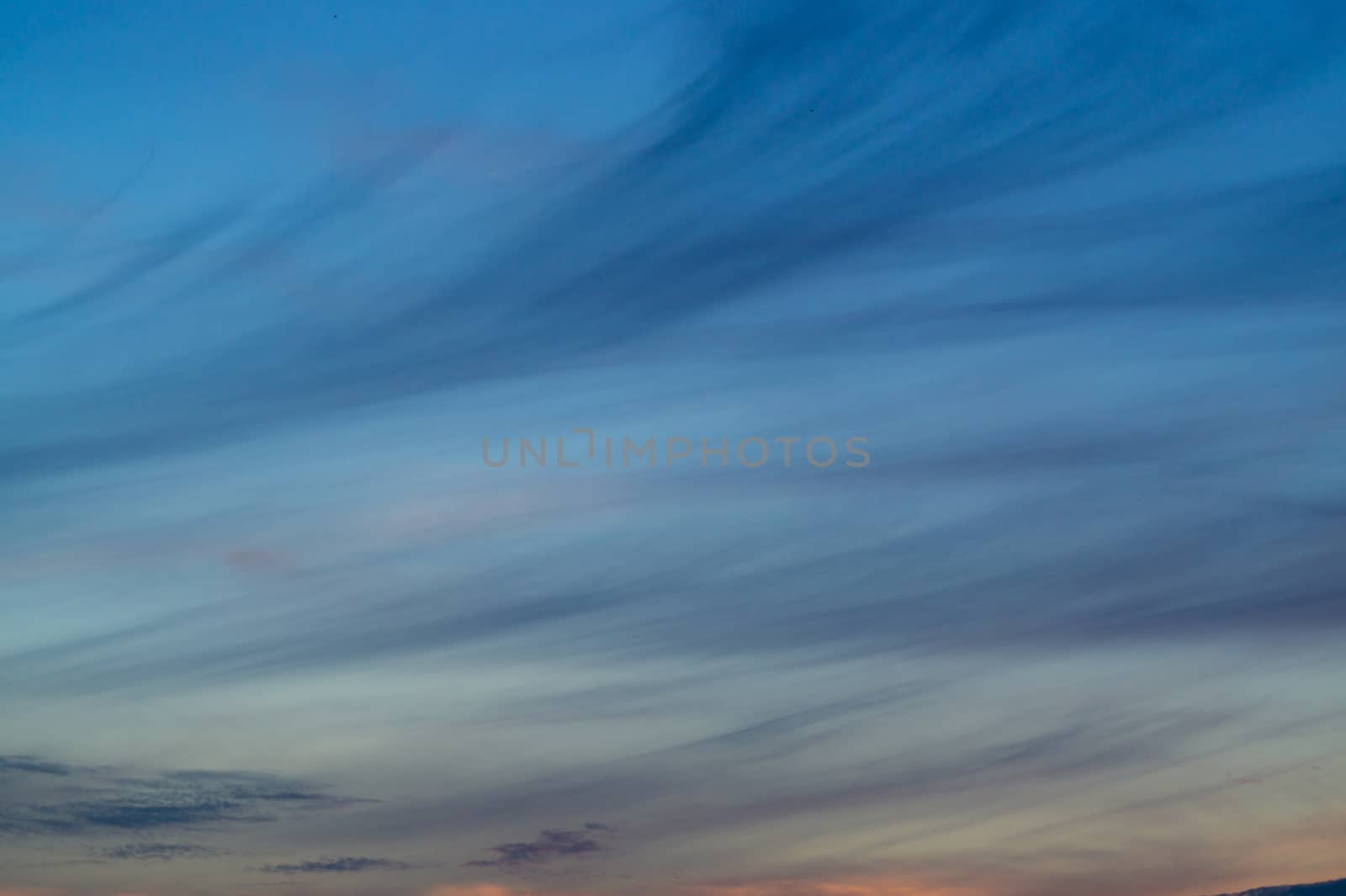 Blue evening sky with blurred sun on horizon trough fence. Creative idea- underexposed photo.