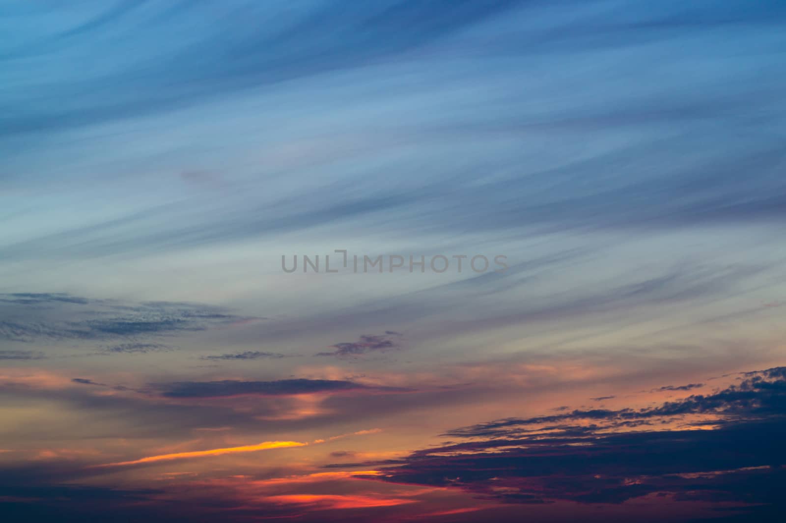 Blue evening sky with blurred sun on horizon trough fence. Creative idea- underexposed photo. by alexsdriver