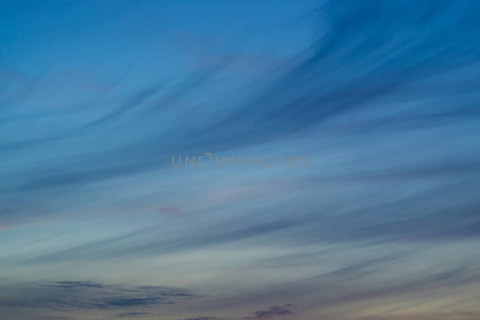 Blue evening sky with blurred sun on horizon trough fence. Creative idea- underexposed photo. by alexsdriver