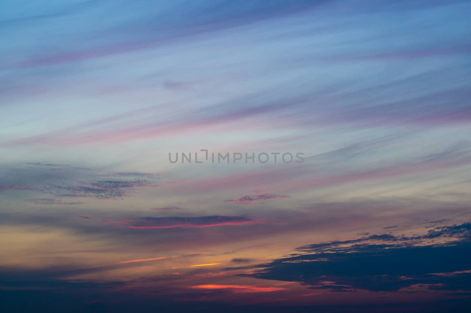 Blue evening sky with blurred sun on horizon trough fence. Creative idea- underexposed photo.