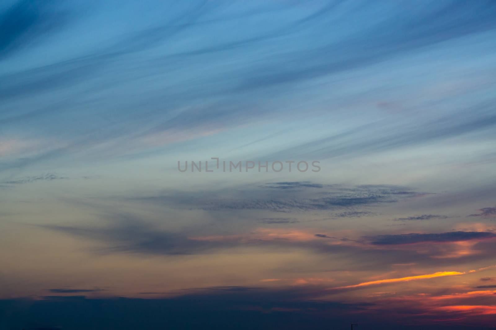 Blue evening sky with blurred sun on horizon trough fence. Creative idea- underexposed photo.