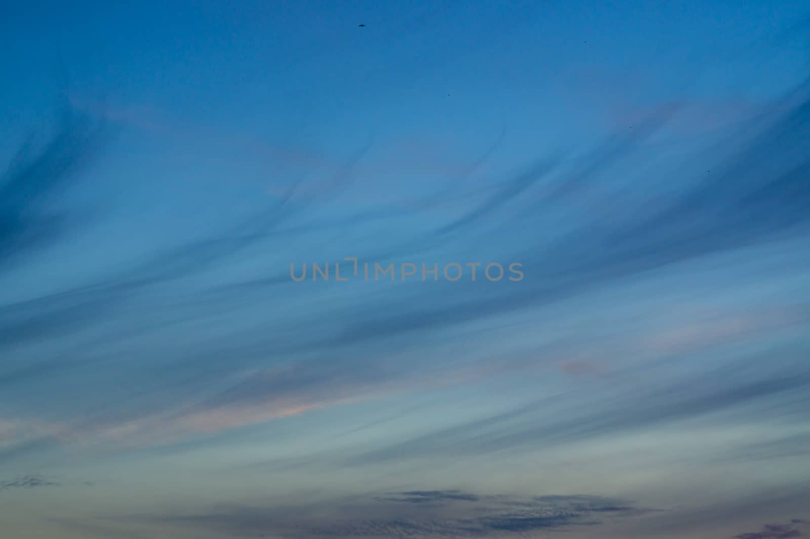 Blue evening sky with blurred sun on horizon trough fence. Creative idea- underexposed photo.