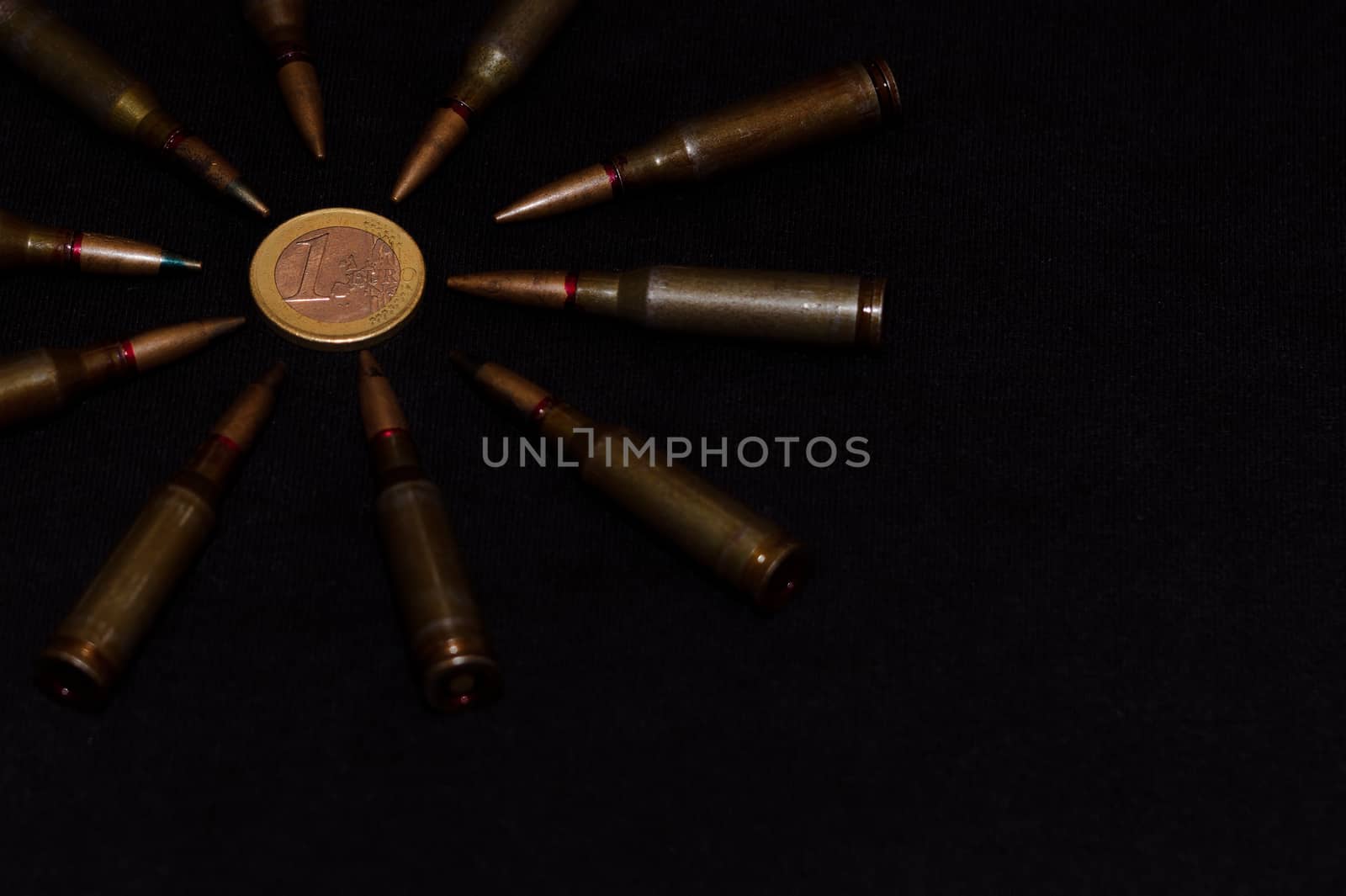Rifle ammo around one euro coin on black background. Symbolizes the war for money and one of the world's problems.