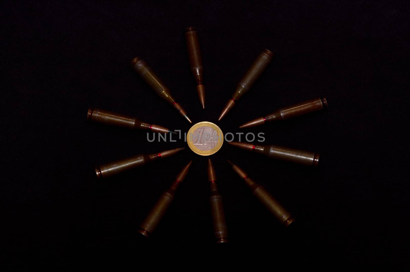 Rifle ammo around one euro coin on black background. Symbolizes the war for money and one of the world's problems.