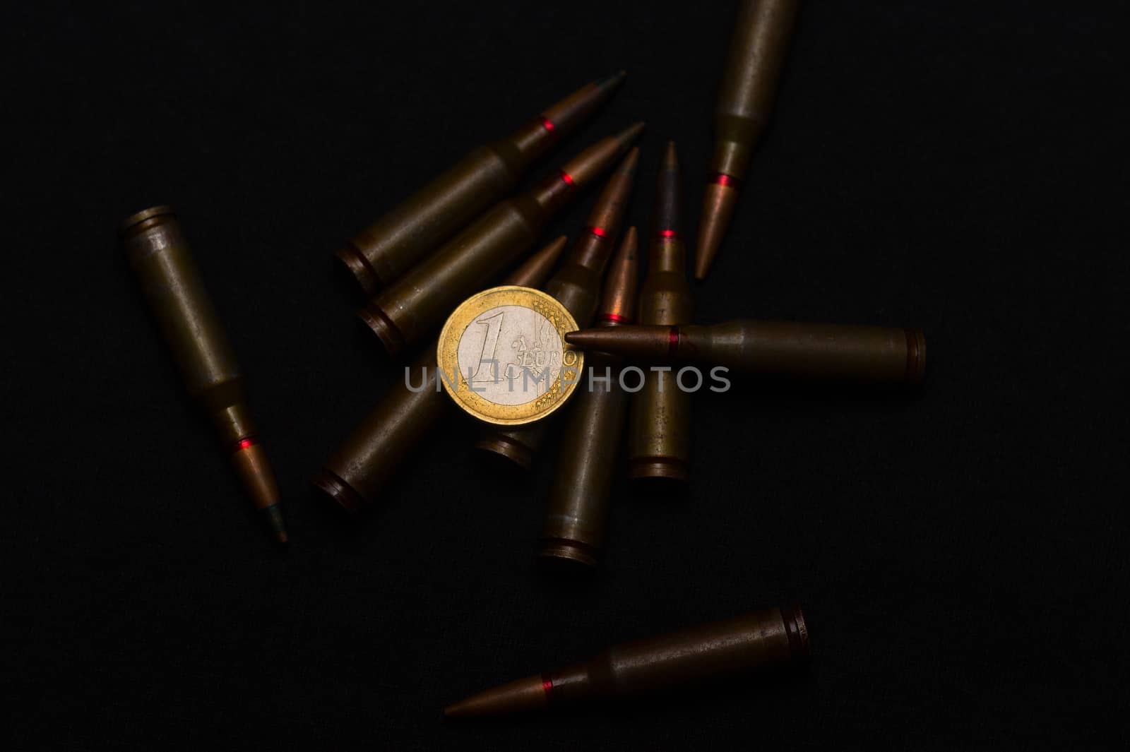 Rifle ammo around one euro coin on black background. Symbolizes the war for money and one of the world's problems.