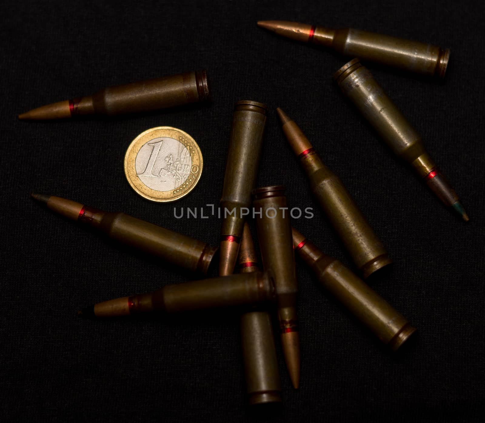 Rifle ammo around one euro coin on black background. Symbolizes the war for money and one of the world's problems. by alexsdriver