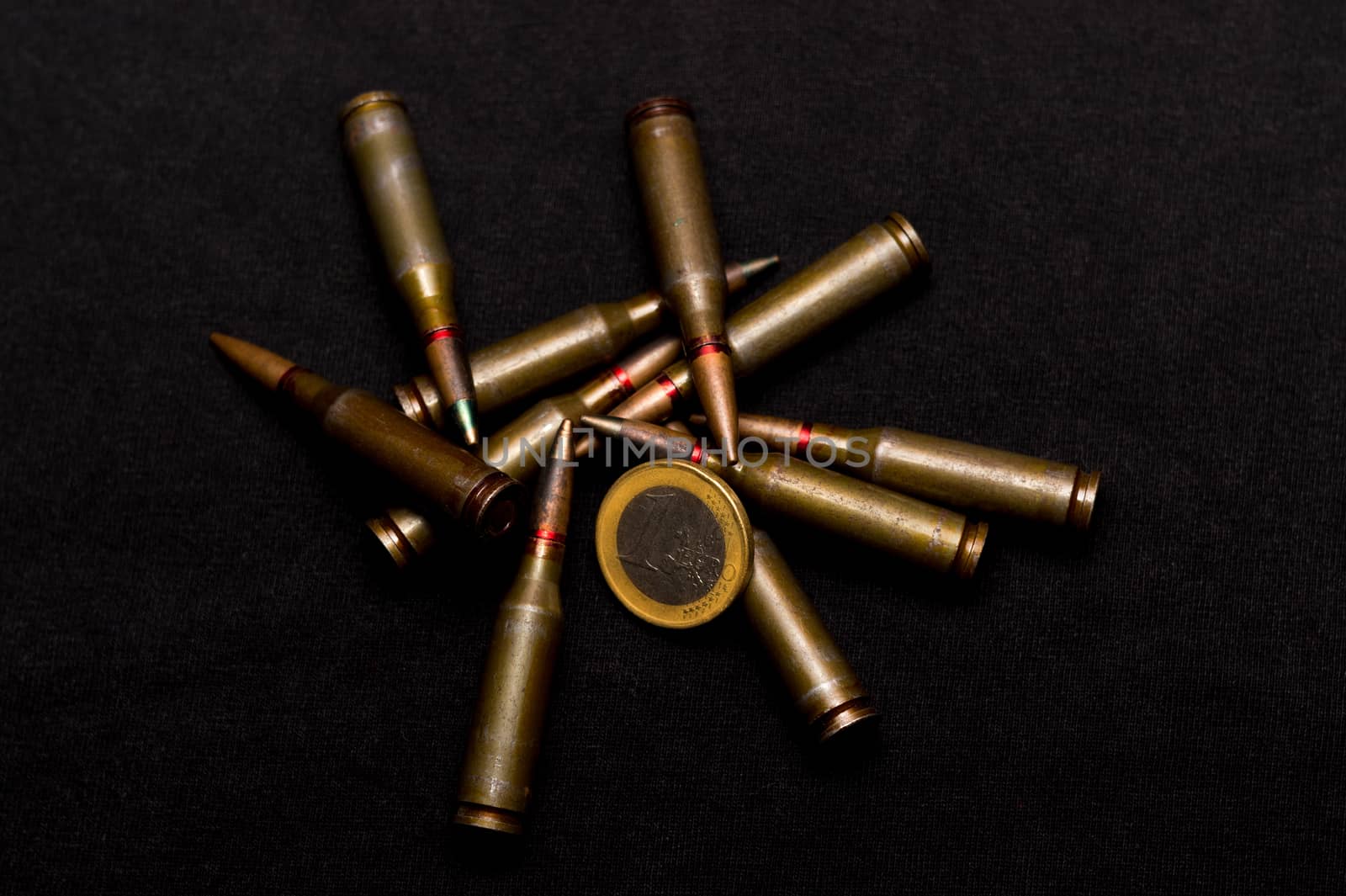 Rifle ammo and one euro coin on black background. Symbolizes the war for money and one of the world's problems.