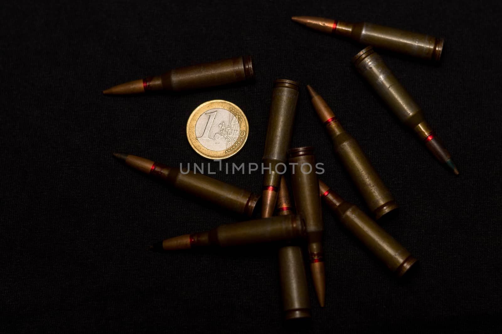 Rifle ammo around one euro coin on black background. Symbolizes the war for money and one of the world's problems.