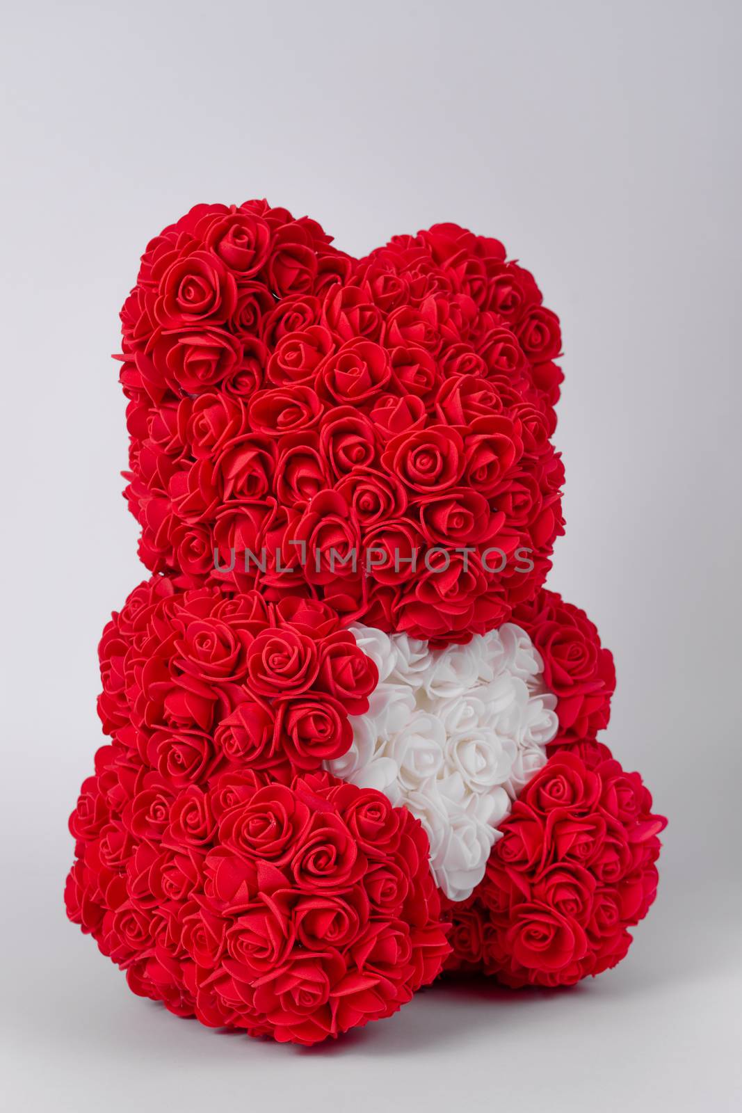 Red  teddy bear toy of foamirane roses. White heart in teddy paws. Stock photo isolated on white background. Perfect gift. by alexsdriver