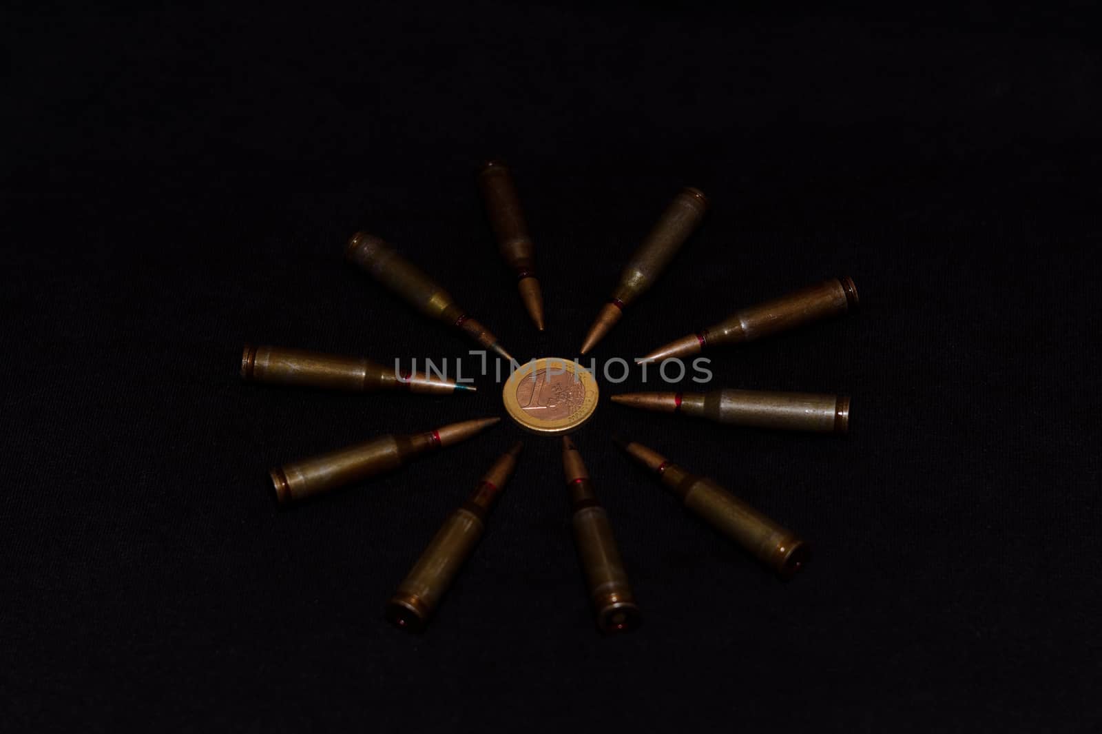 Rifle ammo around one euro coin on black background. Symbolizes the war for money and one of the world's problems. by alexsdriver
