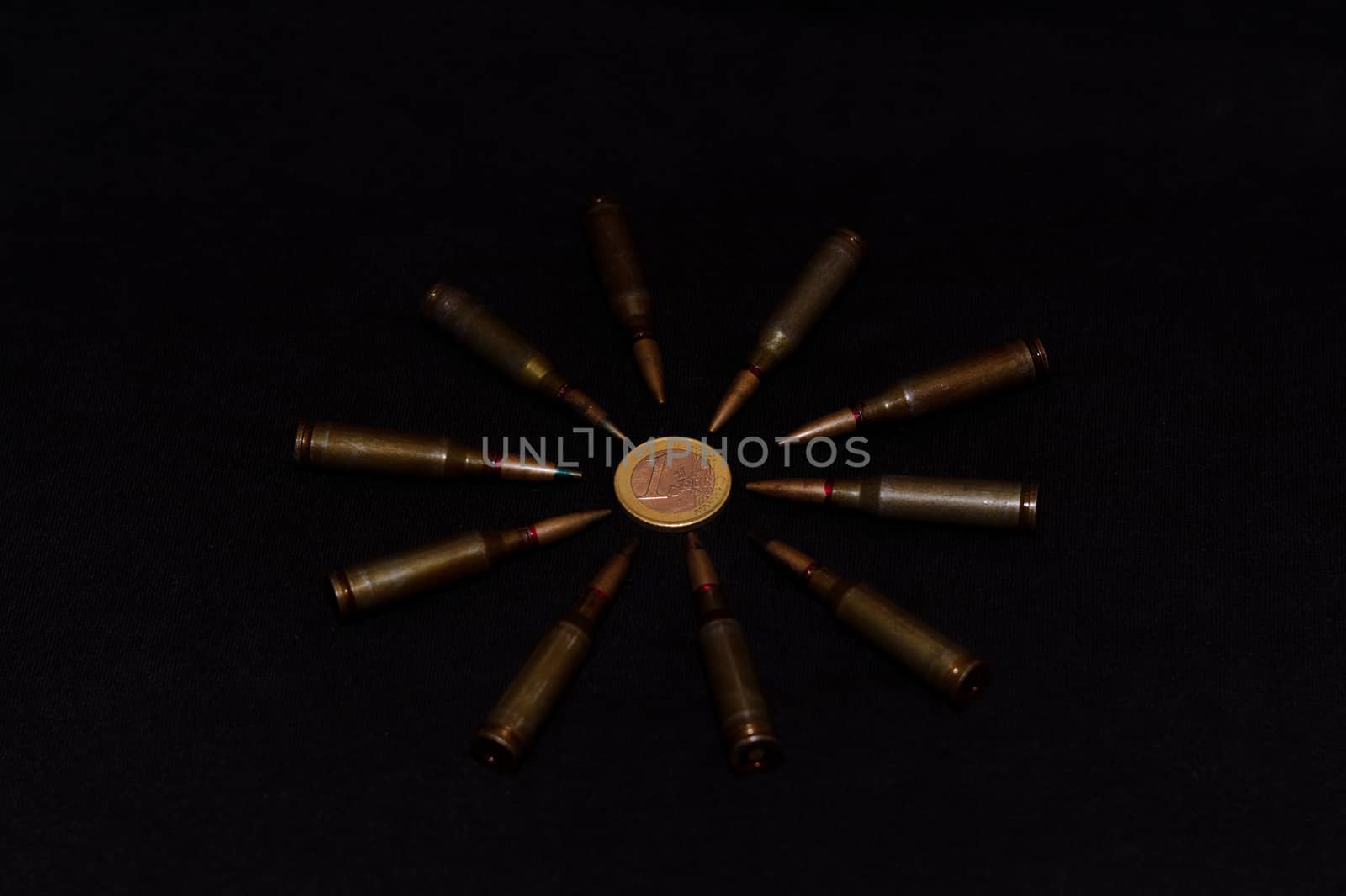 Rifle ammo around one euro coin on black background. Symbolizes the war for money and one of the world's problems.