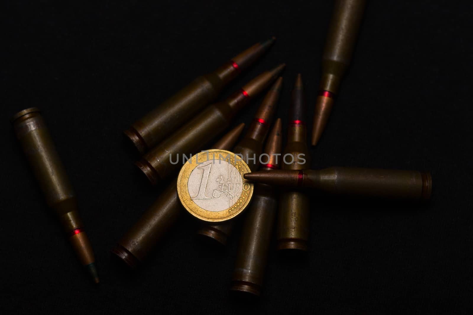 Rifle ammo around one euro coin on black background. Symbolizes the war for money and one of the world's problems. by alexsdriver