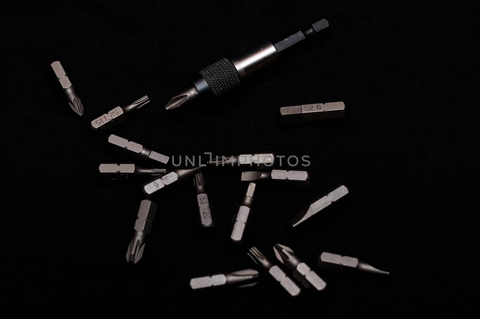 Tool carbon steel bits with bit holder on black background in dark key style.
