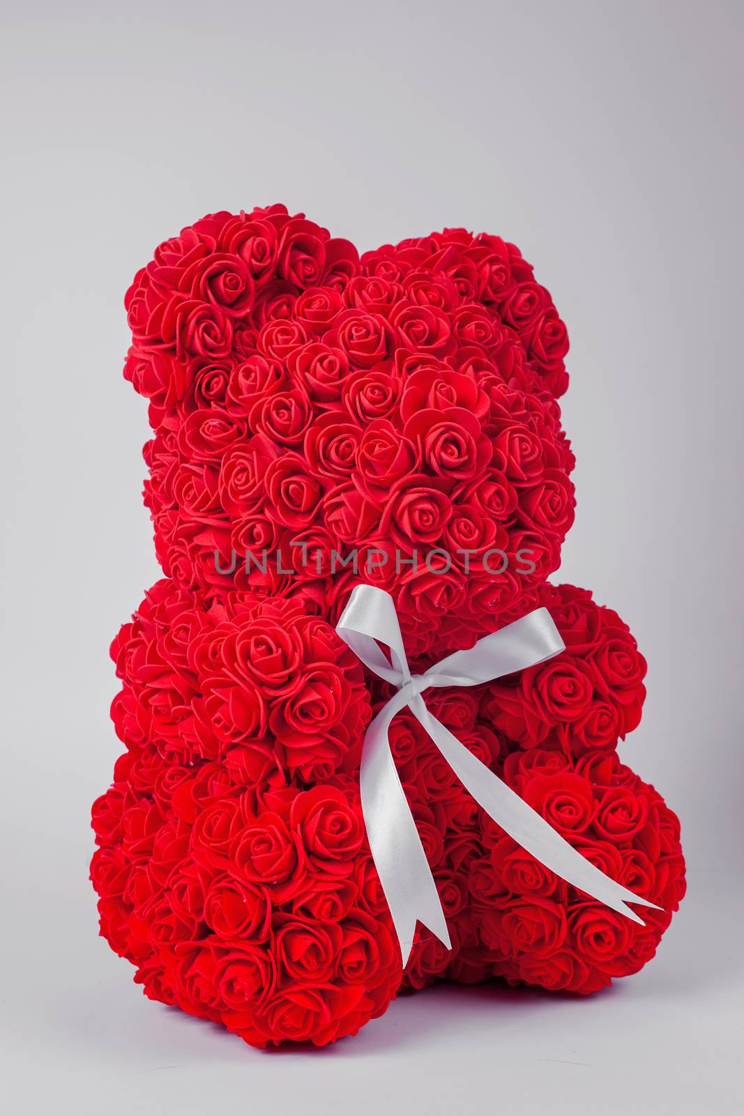 Red  teddy bear toy of foamirane roses. White stripe on teddy neck. Stock photo isolated on white background.