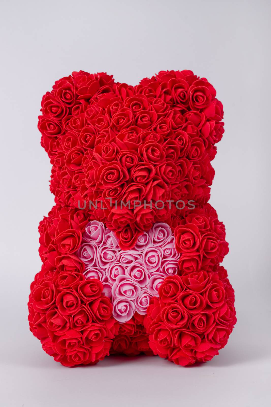 Red  teddy bear toy of foamirane roses. Pink heart in teddy paws. Stock photo isolated on white background.