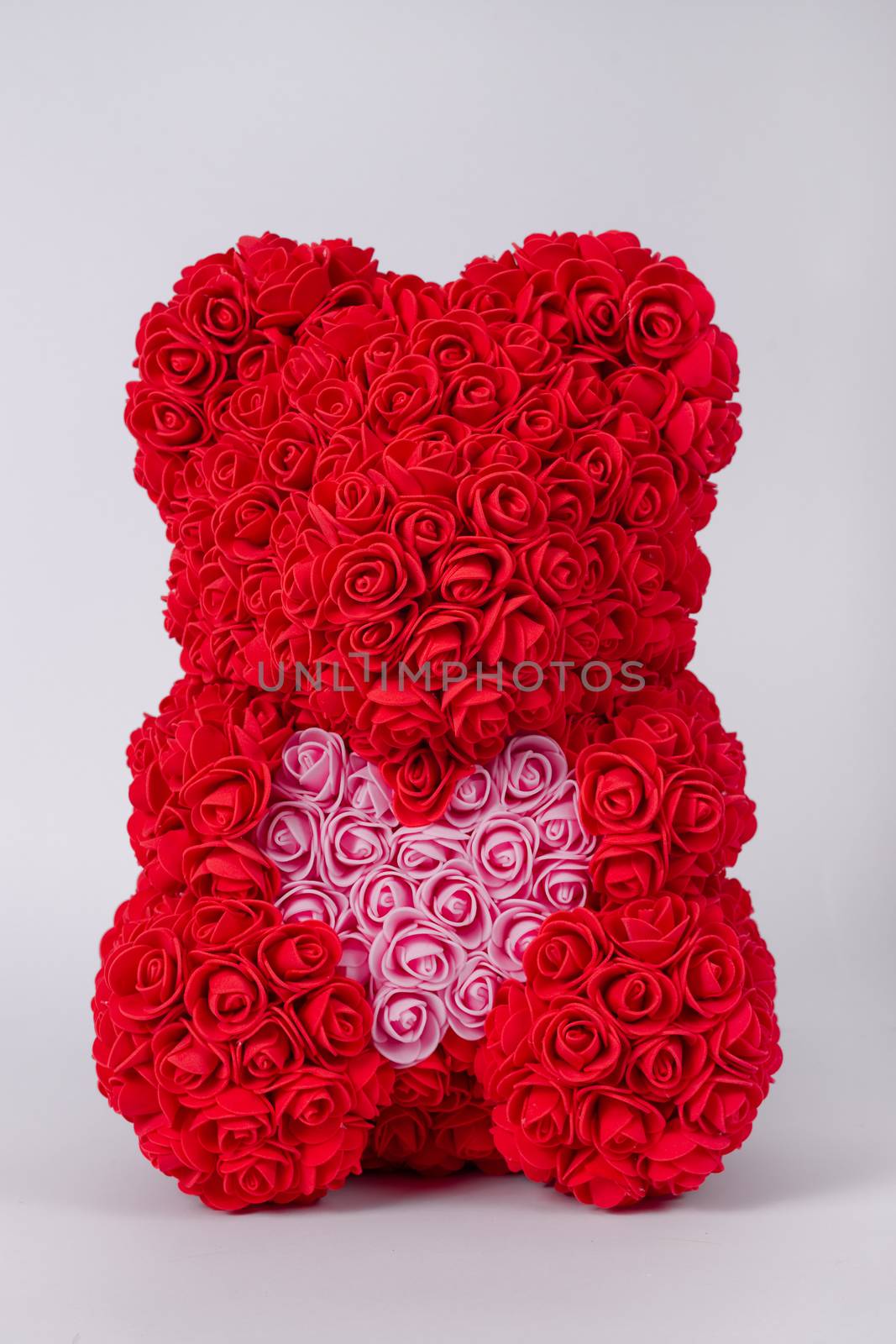 Red  teddy bear toy of foamirane roses. Pink heart in teddy paws. Stock photo isolated on white background.