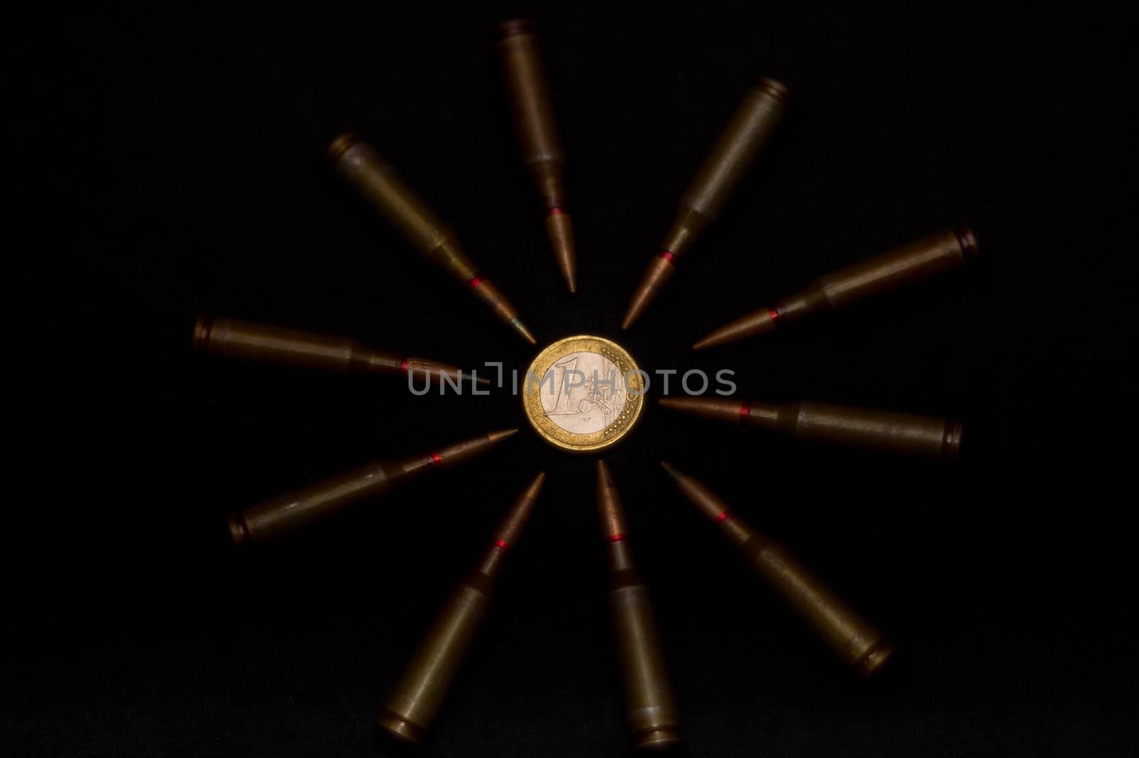 Rifle ammo around one euro coin on black background. Symbolizes the war for money and one of the world's problems.