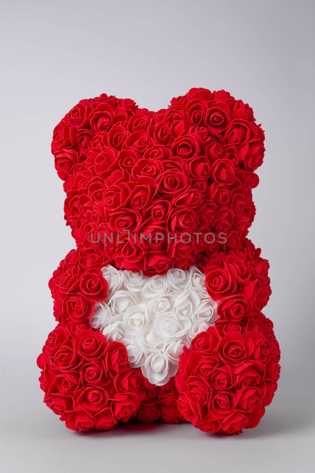 Red  teddy bear of foamirane roses. White heart in teddy paws. Stock photo isolated on white background. by alexsdriver