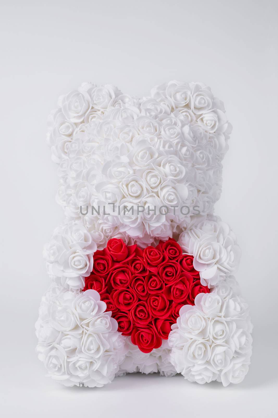 White  teddy bear of foamirane roses. White heart in teddy paws. Stock photo isolated on white background. Perfect gift for women holidays.