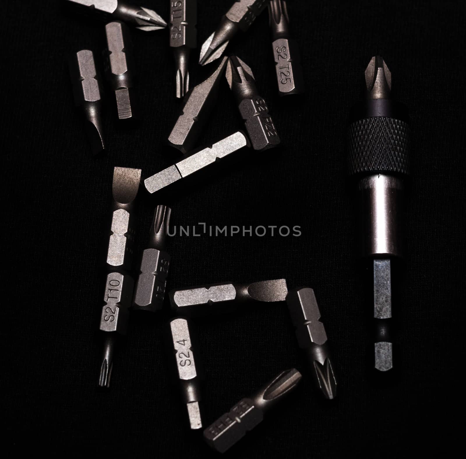Tool carbon steel bits with bit holder on black background in dark key style.