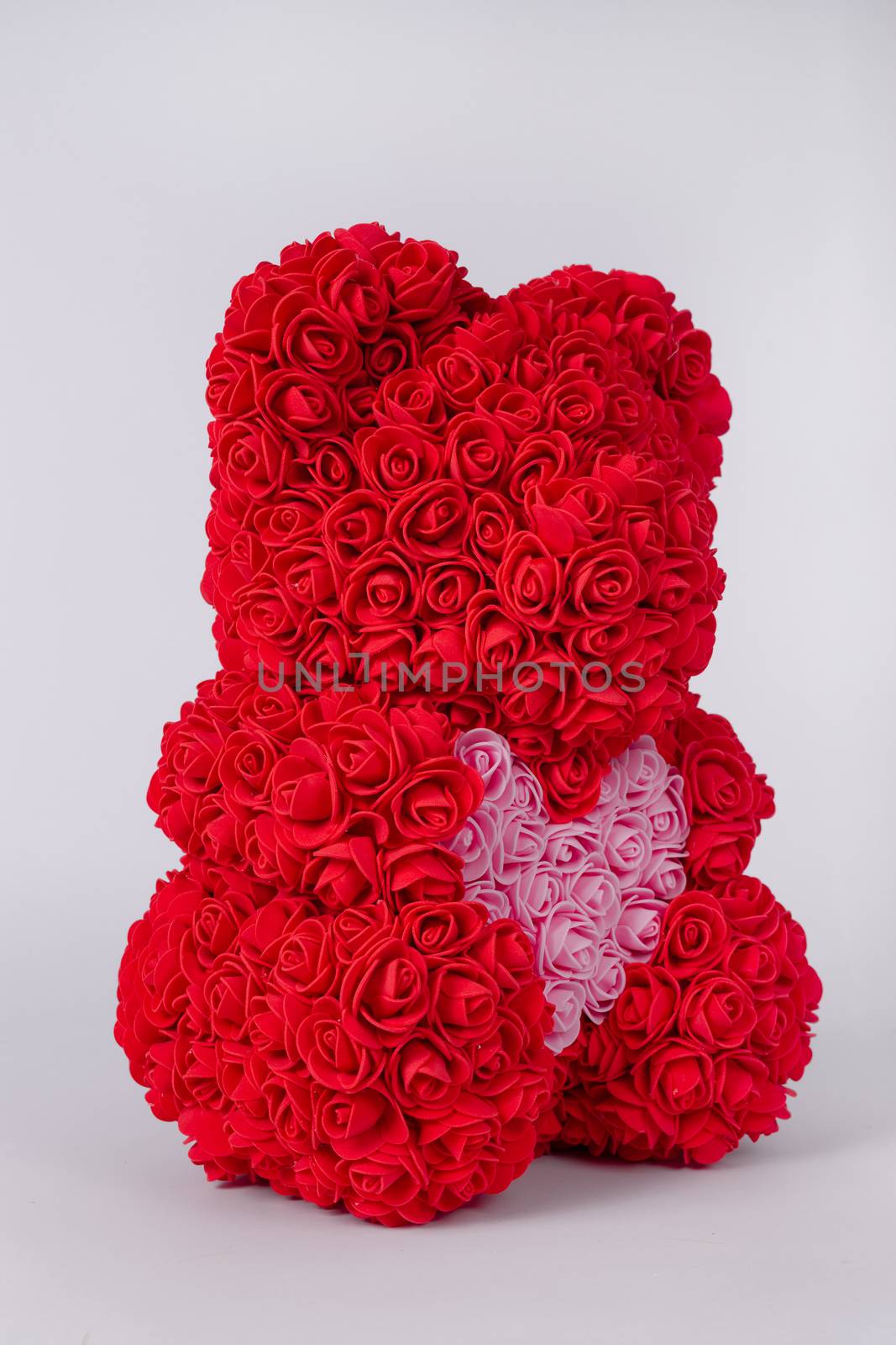 Red  teddy bear toy of foamirane roses. Pink heart in teddy paws. Stock photo isolated on white background.