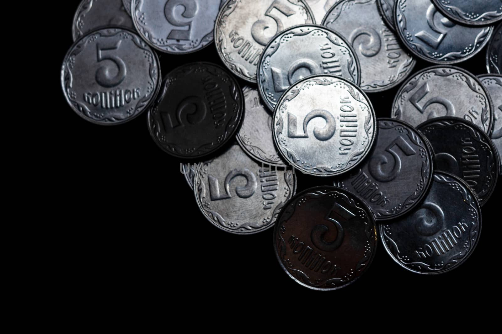 Ukrainian coins isolated on black background. Close-up view. Coins are located above the right side of frame. A conceptual image.