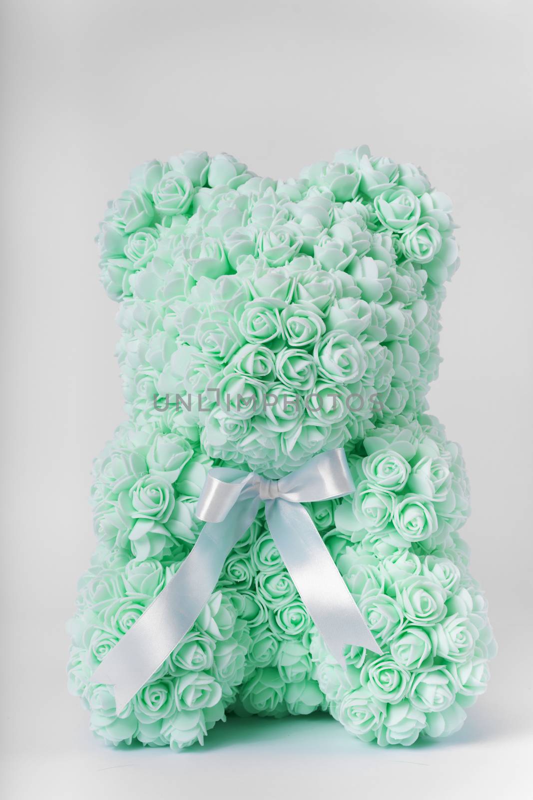 Green teddy bear toy of foamirane roses. White stripe on teddy neck. Stock photo isolated on white background. Gift on holiday for women.