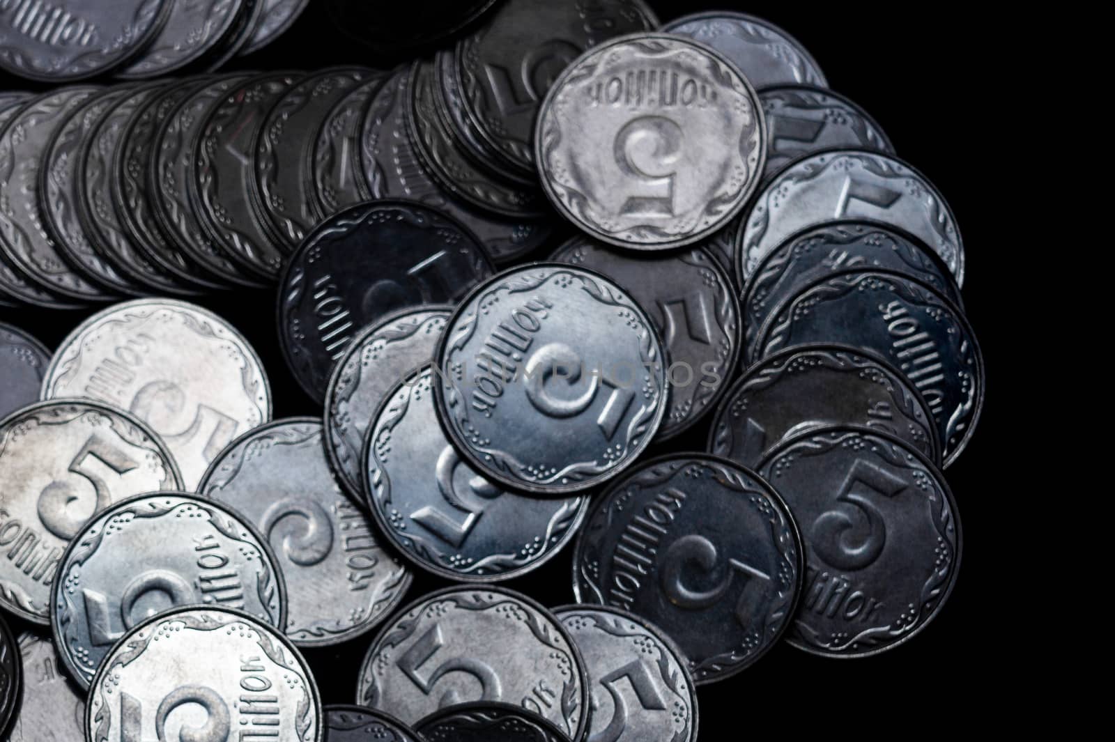 Ukrainian coins isolated on black background. Close-up view. Coins are located above the left side of frame. A conceptual image.