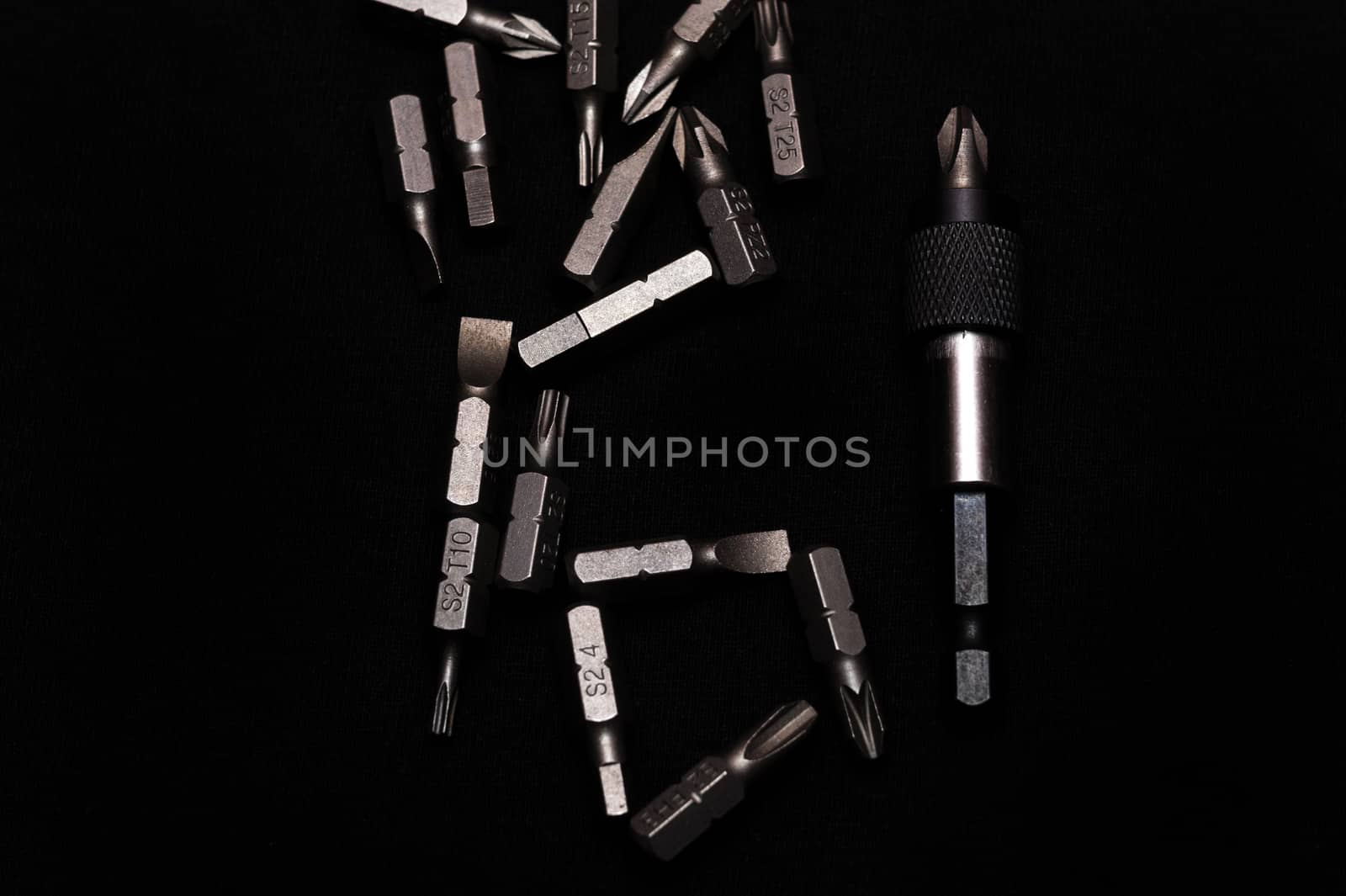 Tool carbon steel bits with bit holder on black background in dark key style.