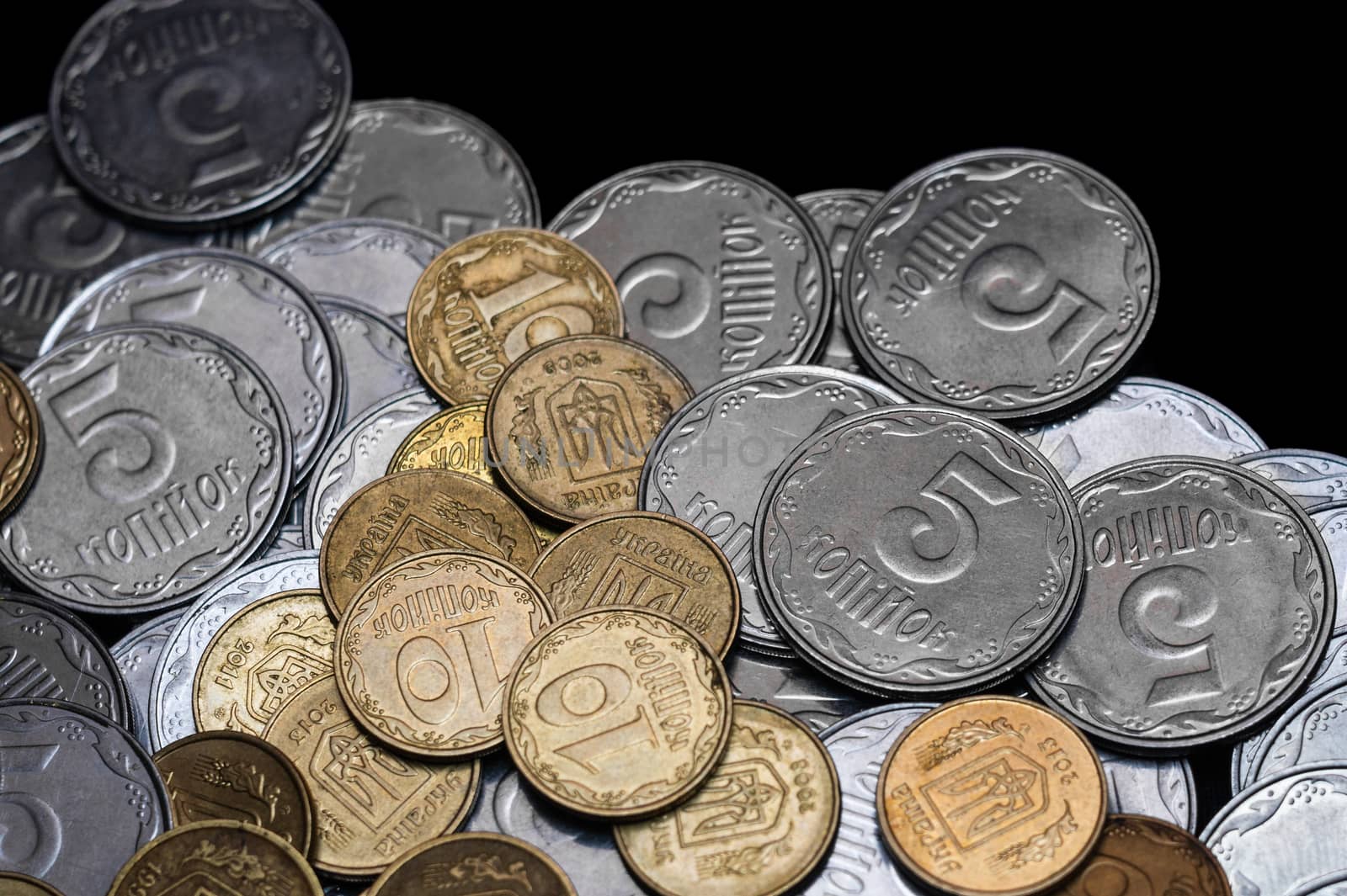 Ukrainian coins isolated on black background. Close-up view. Coins are located below the center of frame. A conceptual image.