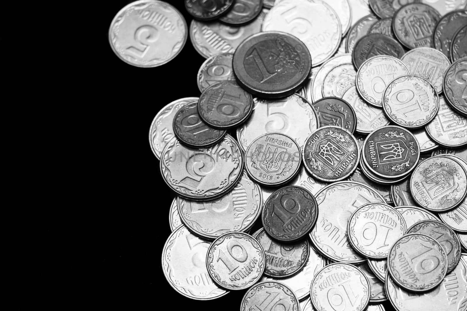 Ukrainian coins with one euro coin isolated on black background. Black and white image. Close-up view. Coins are located at the right side of frame. A conceptual image.