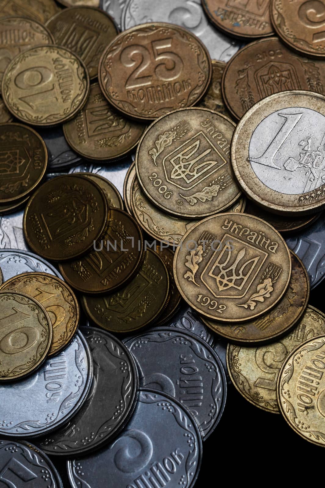 Ukrainian coins with one euro coin isolated on black background. Close-up view. Coins are located at center of frame. A conceptual image. by alexsdriver