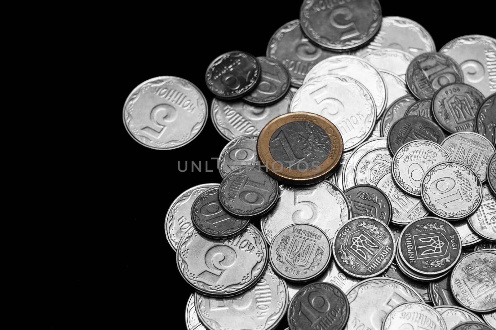 Ukrainian coins isolated on black background. Close-up view. Black and white image. Euro coin is colored. Coins are located at the right side of frame. A conceptual image.