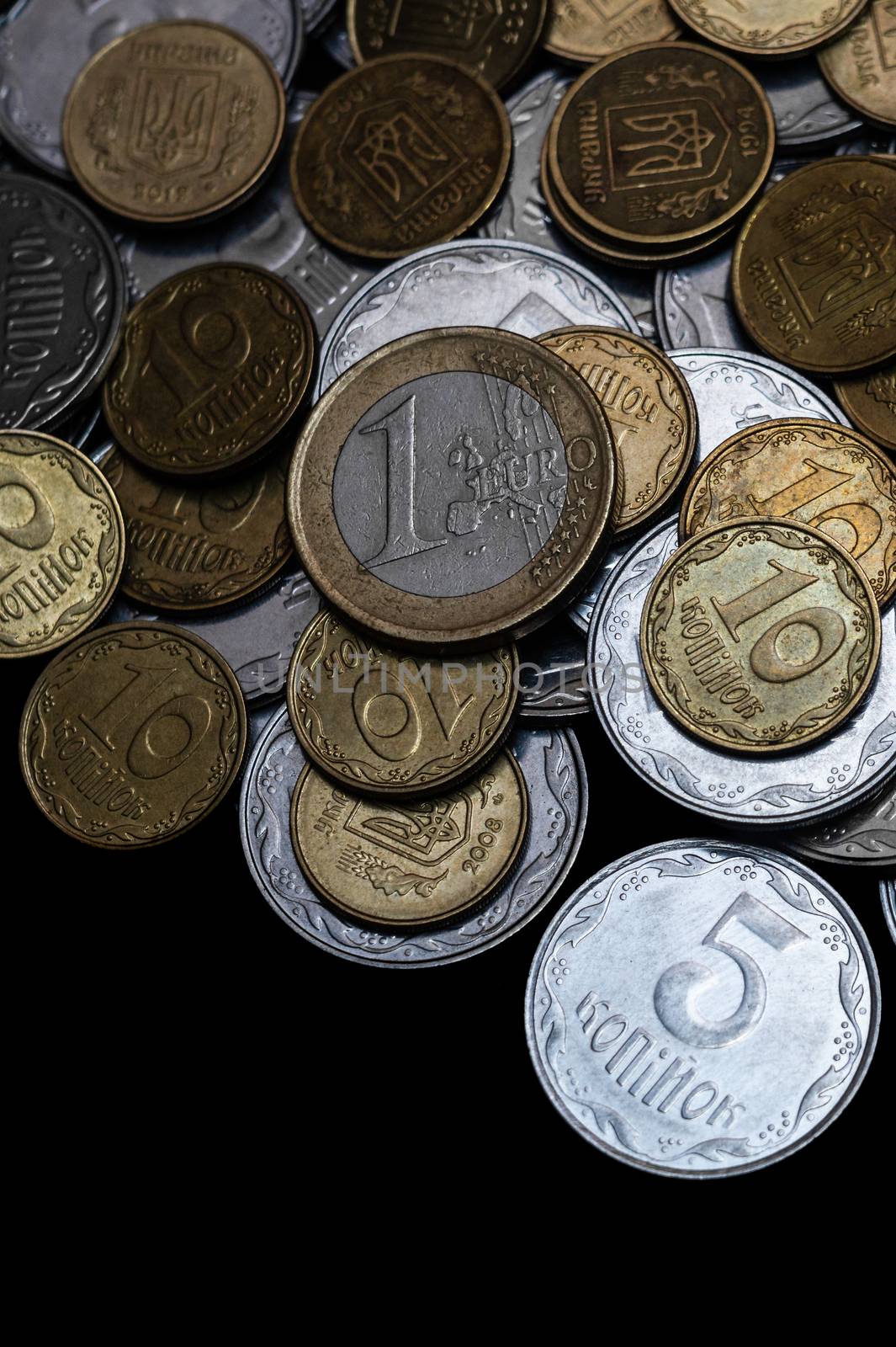 Ukrainian coins with one euro coin isolated on black background. Close-up view. Coins are located at the upper side of frame. A conceptual image. by alexsdriver