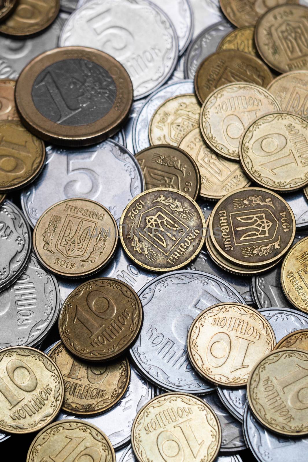 Ukrainian coins with one euro coin isolated on black background. Close-up view. Coins are located at center of frame. A conceptual image.