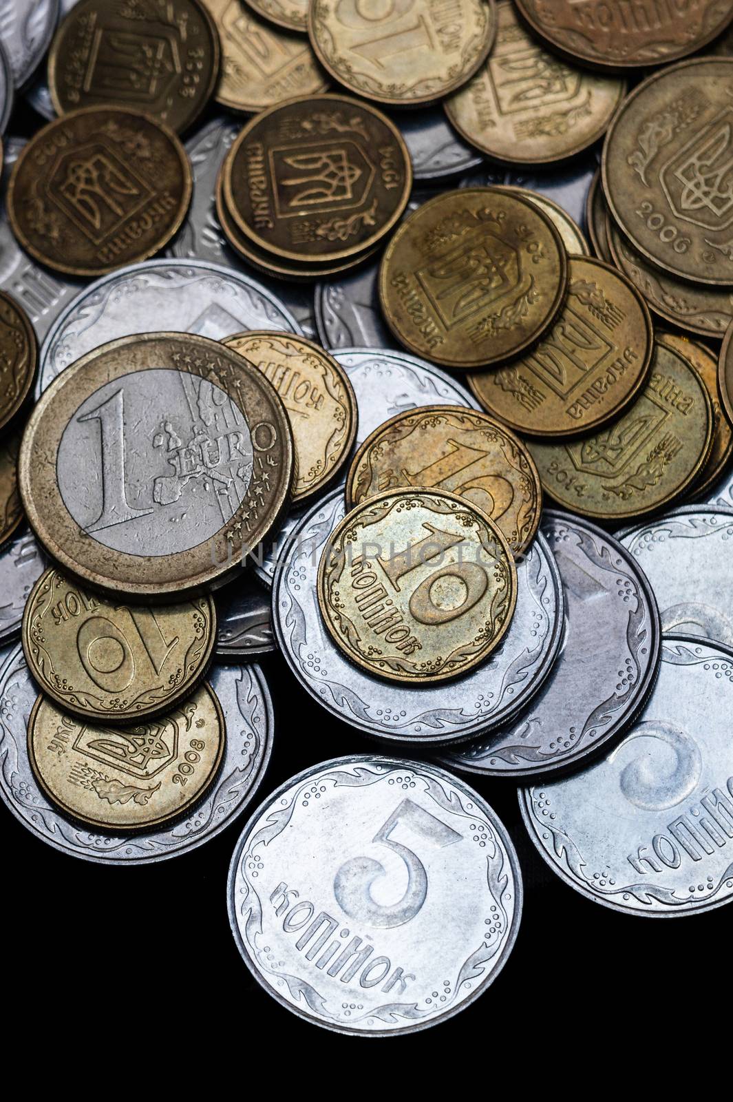 Ukrainian coins with one euro coin isolated on black background. Close-up view. Coins are located at the upper side of frame. A conceptual image. by alexsdriver
