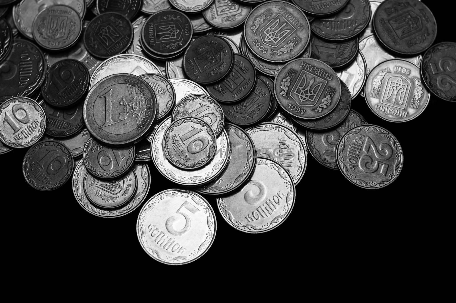 Ukrainian coins with one euro coin isolated on black background. Black and white image.  Close-up view. Coins are located at the upper side of frame. A conceptual image.