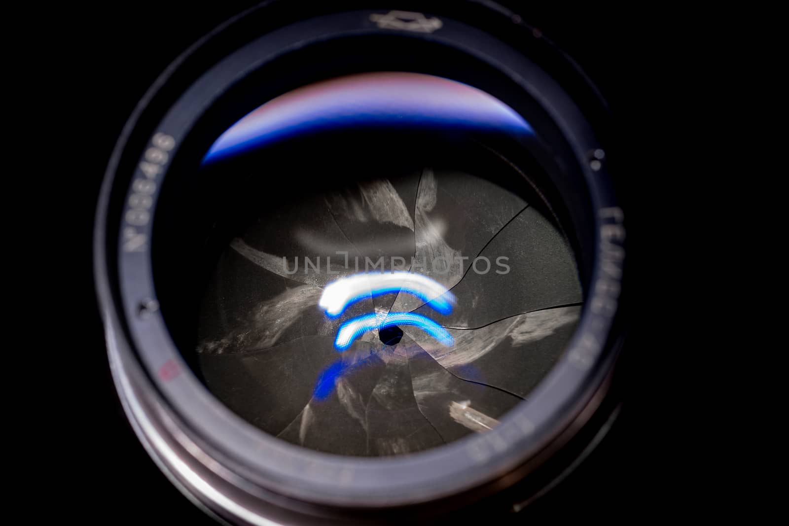 Lens aperture low light photo closeup. Blue traces on glass. Aperture blades is dirty and partially damaged. Stock photo isolated on black background.