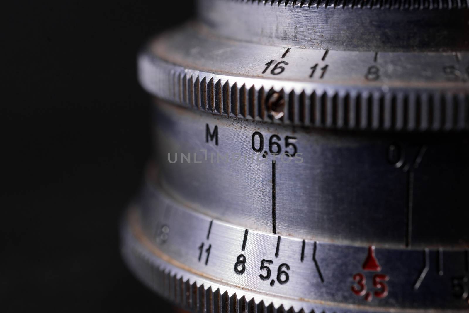 Vintage lens scales symbols closeup. Stock photo with blurred gray background. Aperture symbols and focusing distance sign on lens.